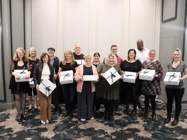 Group of employees holding white boxes, celebrating years of service
