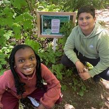 Students sitting next to an Indigenous Plant sign and learning about the plants