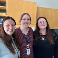 Three female support staff smile for photo