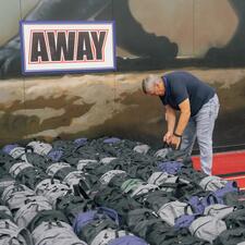Male volunteer learning down to pick up filled backpacks